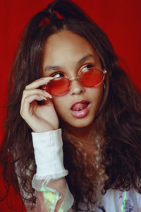 Close-up of teenage girl wearing sunglasses sticking out tongue