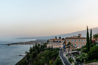 Hotel building in taormina with accommodation for tourists near coast at sunset