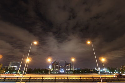 Low angle view of illuminated street light against cloudy sky