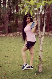 Full length portrait of young woman standing on field