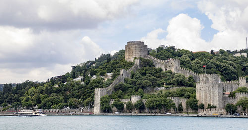 Panoramic shot of castle by river against sky