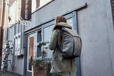 Young woman in urban environment walking into coffee shop