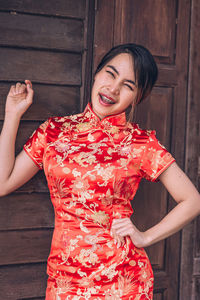 Midsection of woman holding red while standing on wood