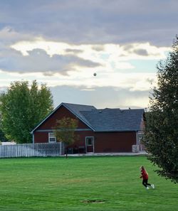 House on field by building against sky