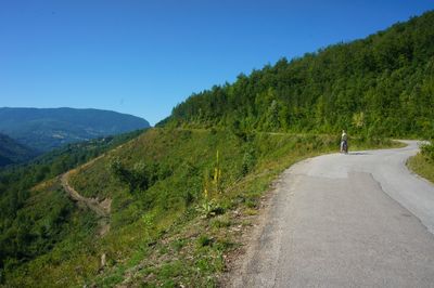 Road amidst green landscape against clear blue sky