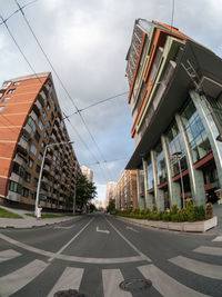 Road by buildings against sky in city