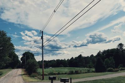 Electricity pylon by road against sky