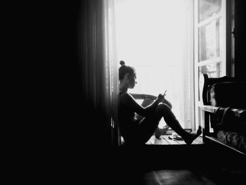 Side view of woman sitting on chair at home