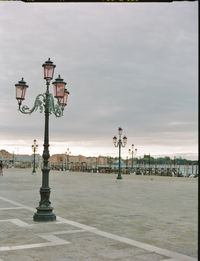 Street light on building against cloudy sky