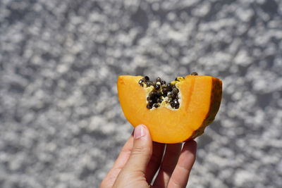 Cropped image of hand holding orange fruit