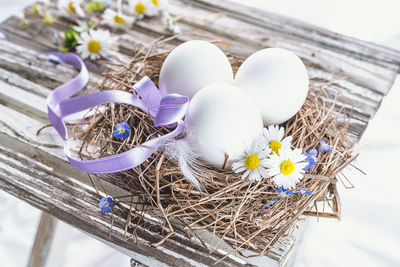 High angle view of eggs in nest by flowers on table