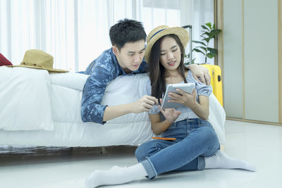Young man using smart phone while sitting on laptop