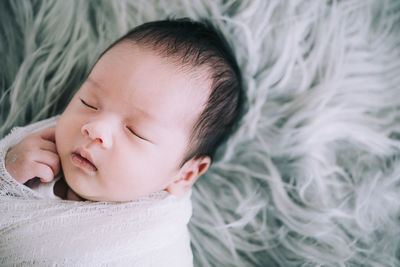 Close-up of baby sleeping in bed