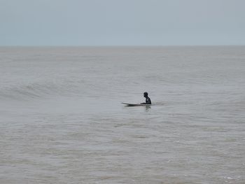 Man swimming in sea against sky