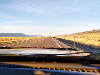 Scenic view of road against sky seen through car windshield