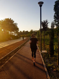 Rear view of woman running in park against sky