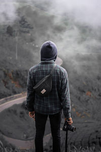 Rear view of man with umbrella walking on street