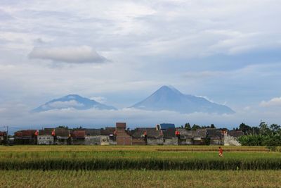 Houses on field by mountains against sky