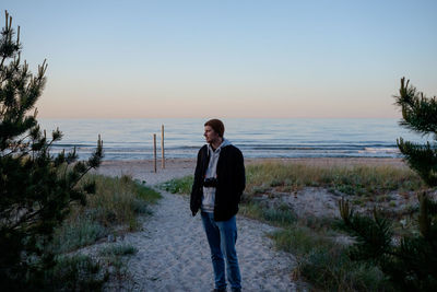 Full length of man standing on beach against sky