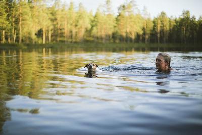 Woman with dog swimming in lake
