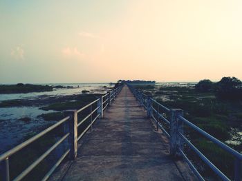 Pier over sea against sky during sunset