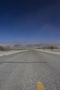 Road by desert against clear sky