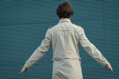 Rear view of businessman standing against corrugated iron