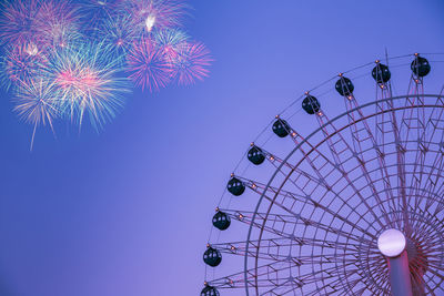 Low angle view of illuminated ferris wheel against sky at night