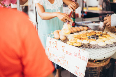 Midsection of woman preparing food at market stall