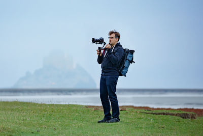 Rear view of man standing on beach against clear sky