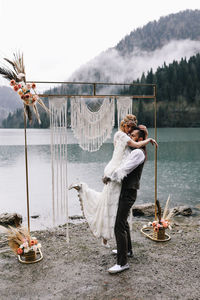 A loving married couple the bride and groom in suits celebrate wedding near the mountains and water