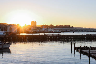 Scenic view of river by buildings against sky during sunset