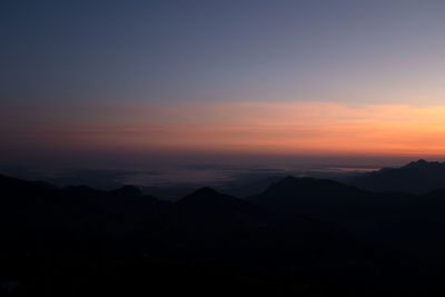 Scenic view of silhouette mountains against romantic sky at sunset