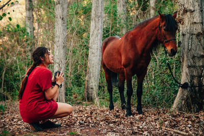 Side view of woman by horse in forest