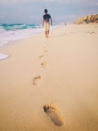 Rear view of man walking on beach