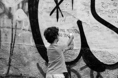 Rear view of boy standing against wall