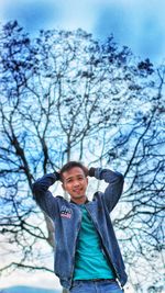 Portrait of smiling boy standing against bare tree