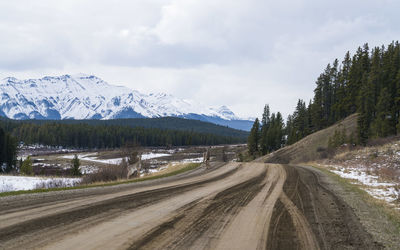 Road amidst snowcapped mountains against sky