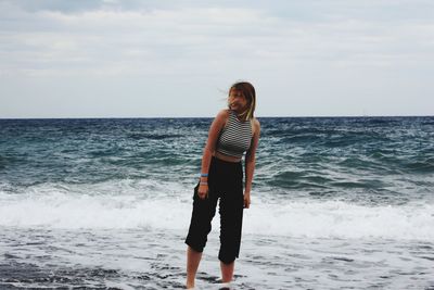 Woman standing in sea against sky