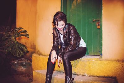 Full length portrait of young woman sitting outdoors