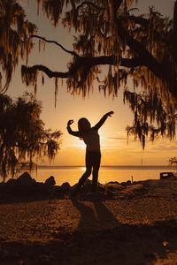 Silhouette person standing on beach against sky during sunset