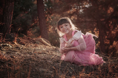 Portrait of cute girl smiling while crouching on field