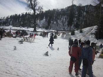 People on snow covered landscape against sky