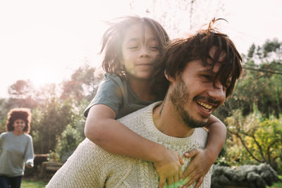 Father carrying son piggyback in a garden in the countryside