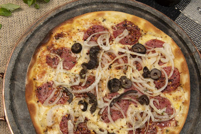 Brazilian pizza with pepperoni, cheese, onion and black olive , top view