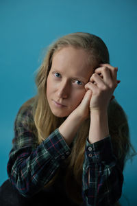 Portrait of young woman against blue background