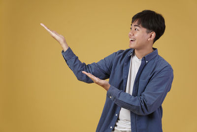 Man looking away while standing against yellow background