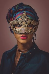 Close-up portrait of woman wearing mask against colored background