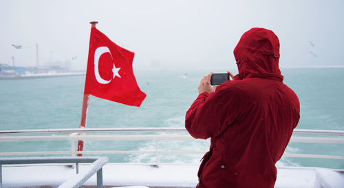 Rear view of man standing by railing against sea