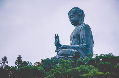 Low angle view of statue against trees against sky